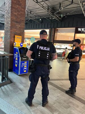 Dwaj policjanci stoją przy bankomacie.
