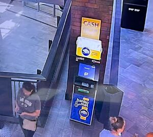 Wnętrze galerii handlowej. Bankomat i przechodzące osoby.