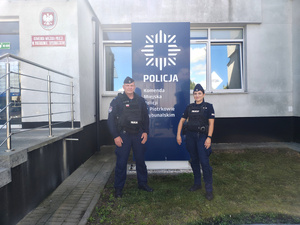 policjant i policjantka stoją przy budynku Policji.