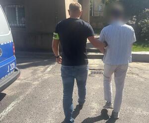 Mężczyzna prowadzony przez policjanta.