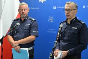 Dwaj funkcjonariusze stoją przy mikrofonach podczas konferencji.
