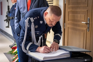 Komendant Główny Policji gen. insp. Marek Boroń wpisuje się do księgi pamięci.