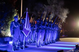 Funkcjonariusze kompanii reprezentacyjne Policji stoją podczas uroczystości w dwuszeregu oddając strzały z karabinu.