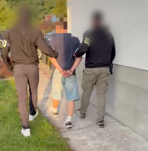 Policja prowadzi zatrzymanego mężczyznę.