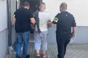 Policja prowadzi zatrzymanego mężczyznę.