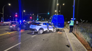 Rozbite samochody na drodze. Obok na poboczu policjant.