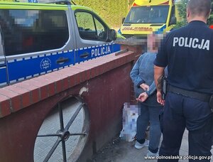 Policjant odprowadza odnalezioną kobietę.