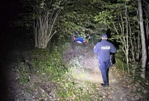 Policjanci w terenie zalesionym podczas poszukiwania zagubionej kobiety.