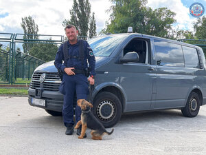 Policjant z psem przy radiowozie.