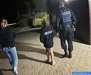 Policjant z dziewczynka i jej mamą idą chodnikiem.