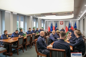 Komendant Główny Policji oraz I Zastępca Komendanta Głównego Policji i dyrektor Biura Prewencji Policji siedzą przy stole podczas spotkania z policjantami.