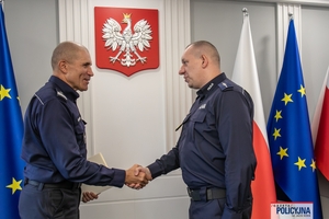 I Zastępca Komendanta Głównego Policji ściska dłoń funkcjonariuszowi gratulując.