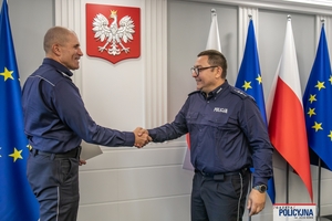 I Zastępca Komendanta Głównego Policji ściska dłoń funkcjonariuszowi gratulując.