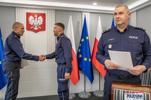 I Zastępca Komendanta Głównego Policji ściska dłoń funkcjonariuszowi gratulując.