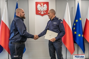 I Zastępca Komendanta Głównego Policji ściska dłoń funkcjonariuszowi gratulując.