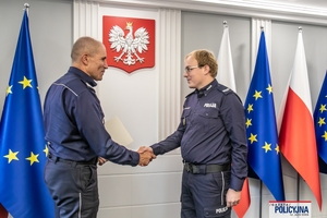 I Zastępca Komendanta Głównego Policji ściska dłoń funkcjonariuszowi gratulując.