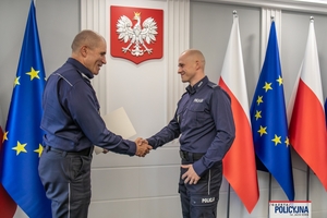 I Zastępca Komendanta Głównego Policji ściska dłoń funkcjonariuszowi gratulując.