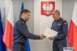 I Zastępca Komendanta Głównego Policji ściska dłoń funkcjonariuszowi gratulując.