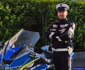 Policjant stoi przy motocyklu.
