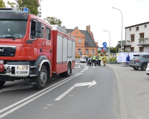 Wóz straży pożarnej z policjantami w tle.