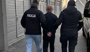 Dwaj funkcjonariusze prowadzą zatrzymanego.