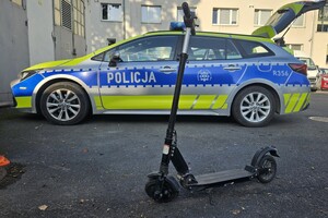 N pierwszym planie uszkodzona hulajnoga, w tle radiowóz.