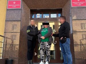 Dwaj policjanci z zatrzymaną kobietą przy drzwiach wejściowych do prokuratury.