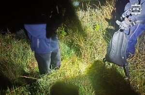 Odnaleziony nastolatek i trzymający plecak policjant - pora nocna.