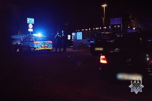 Policjanci obok radiowozu w trakcie interwencji.