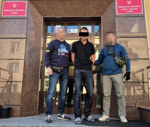 Policjanci w cywilu wyprowadzają zatrzymanego mężczyznę.