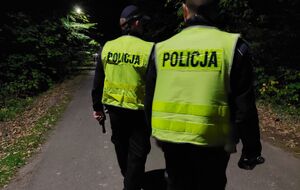 Policjanci przeszukują las w nocy.