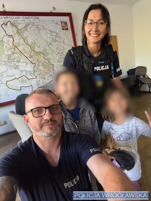 Dwoje policjantów pozuje do zdjęcia z dwójką dzieci.