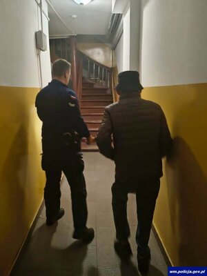 Policjant odprowadza starszego mężczyznę do domu.