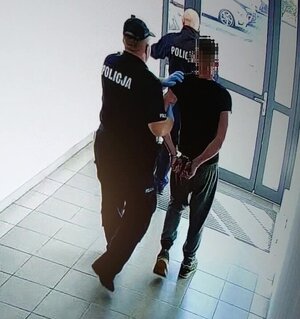 Policjanci prowadzą zatrzymanego.
