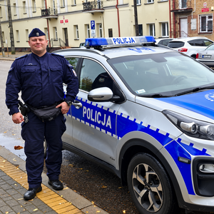 Dzielnicowy obok radiowozu.