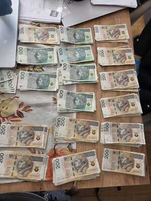 Banknoty leżą rozłożone na blacie.