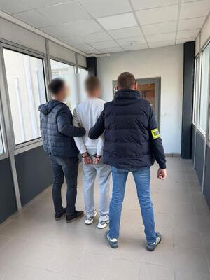 Dwaj policjanci prowadzą zatrzymanego.