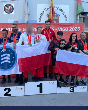 Grupa zawodników na podium. Dwie drużyny trzymają polskie flagi, jedna z drużyn trzyma flagę z logo Frontex.