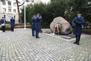 komendant składa wieniec na grobie.