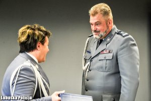 Komendant Wojewódzki Policji wręcza prezent policjantowi.
