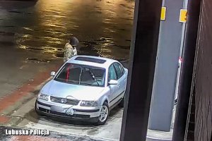 Zakapturzony człowiek przy samochodzie na stacji paliw