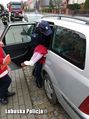 Policjantka wyciąga dziecko z samochodu