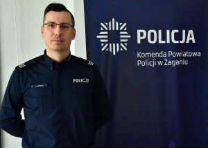 Policjant stojący przy banerze policyjnym.