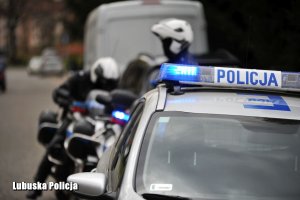Policjanci przy motocyklach i radiowozie