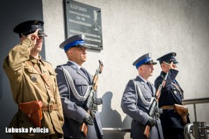 Policjanci przed tablicą upamiętniającą patrona Lubuskiej Policji.