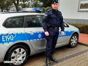 policjant stoi przed radiowozem