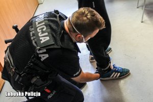 policjant zakłada kajdanki podejrzanemu