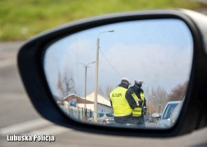Policjanci podczas kontroli drogowych - odbicie w lusterku bocznym.