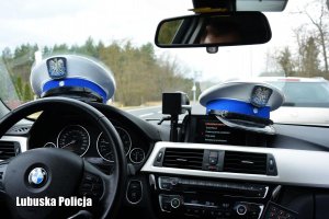 Czapki policjantów ruchu drogowego na kokpicie radiowozu