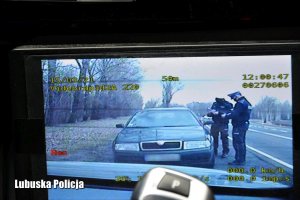 Widok z radiowozu na wyświetlacz videorejestratora, gdzie są widoczni policjantów kontrolujących kierowcę